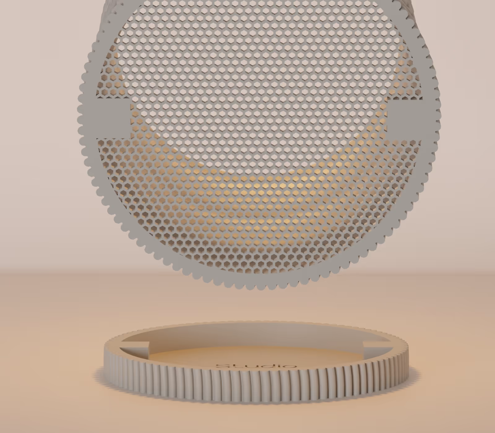 Close-up of a beige circular honeycomb-patterned object suspended above a matching base labeled Studio.
