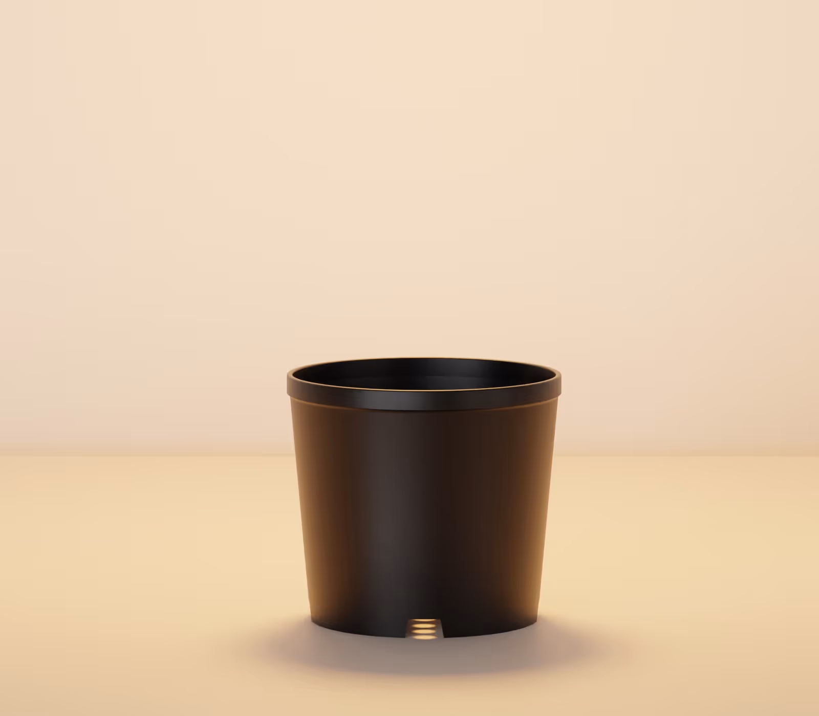 Black plastic plant pot with drainage hole on a beige surface against beige background.